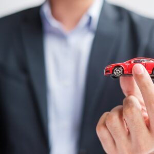 Businessman hand holding red car toy. Car insurance, warranty, rental, Financial, new and repair con